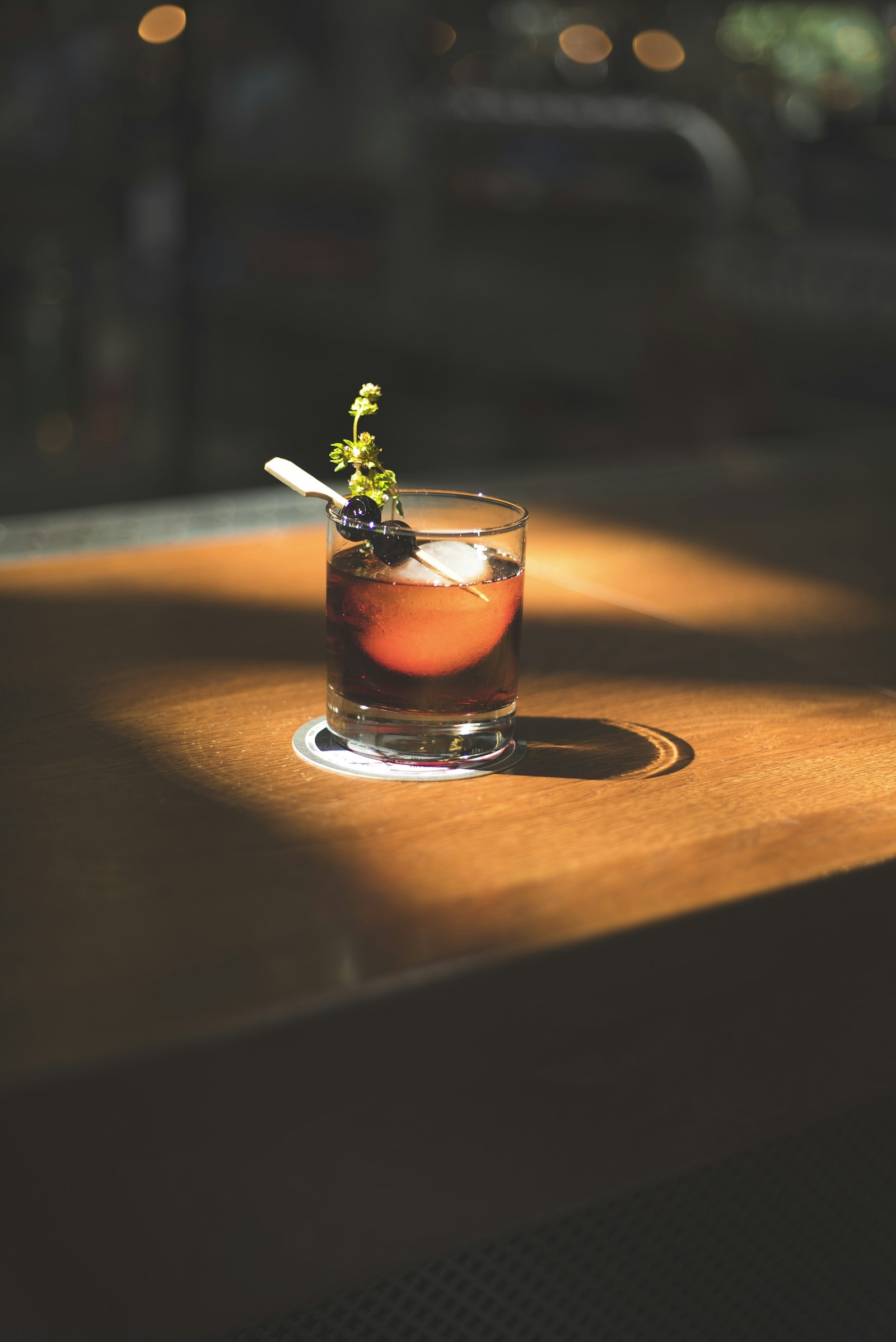 Trago color ámbar con hielo sobre mesa de madera